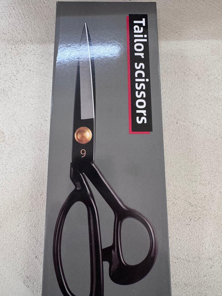 A box of Super Cheap Fabrics Tailor Scissors 9” Dressmaking Shears with black handles, gold screw, ergonomic design, and "Tailor scissors" in white and red on a gray background.