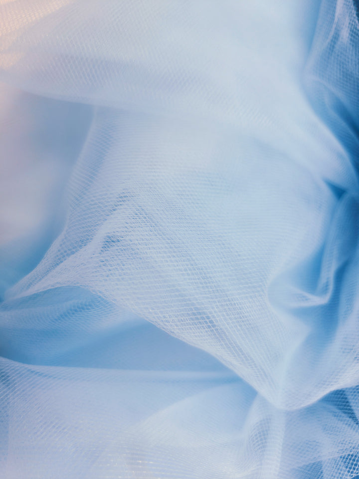 Super Cheap Fabrics' Soft Tulle - Spun Sugar (150cm) features delicate, sheer light blue fabric with gentle folds—perfect for dreamy bridal veils or creative craft projects.