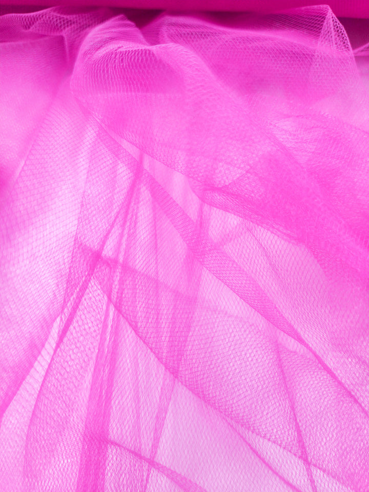 Soft Tulle - Very Berry by Super Cheap Fabrics (150cm) features bright pink, lightweight, and translucent layers with fine mesh—ideal for costumes or elegant bridal veils. Its airy texture and delicate folds add a soft, sophisticated touch.