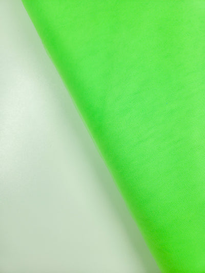 A close-up of Super Cheap Fabrics’ Soft Tulle in Neon Lime (150cm) draped diagonally, showcasing its bright green hue, soft texture, and gentle folds—ideal for bridal veils or costumes.