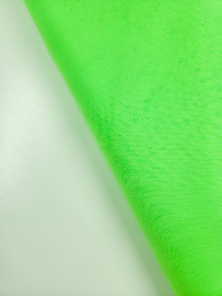 A close-up of Super Cheap Fabrics’ Soft Tulle in Neon Lime (150cm) draped diagonally, showcasing its bright green hue, soft texture, and gentle folds—ideal for bridal veils or costumes.