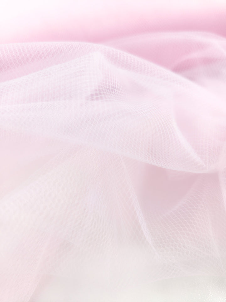 The Soft Tulle - Baby Pink - 150cm from Super Cheap Fabrics features soft, sheer layers of pale pink tulle for a delicate, airy look, perfect for bridal veils or costumes with subtle folds and gentle gradients.