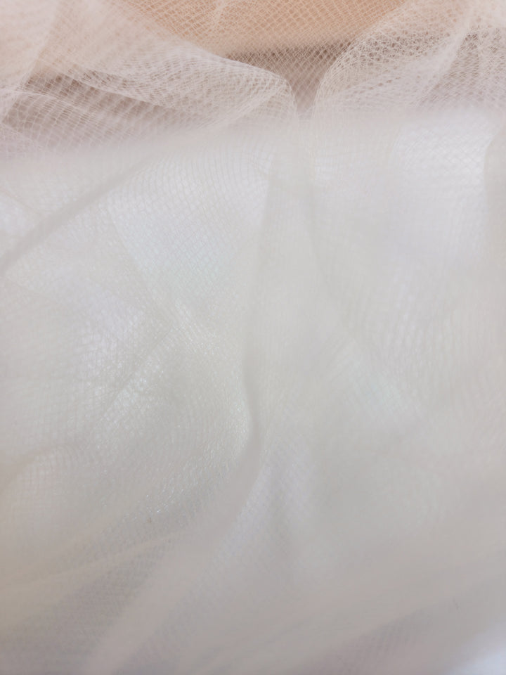 Close-up of Soft Tulle - Peach - 150cm by Super Cheap Fabrics, showing its delicate, airy layers and sheer texture, reminiscent of bridal veils with subtle light and shadow variations.