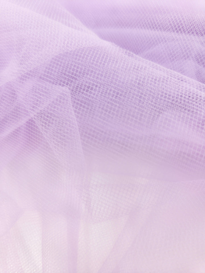 A close-up of Super Cheap Fabrics’ Soft Tulle - Lavender - 150cm shows sheer, pastel layers with a fine mesh texture—ideal for craft projects or elegant bridal veils in a dreamy, ethereal style.