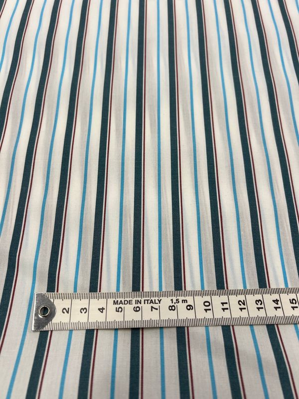 A close-up of Super Cheap Fabrics' Shirting - Marquee - 150cm shows blue, black, and thin red stripes on white polyester cotton. A "Made in Italy" measuring tape spans 18cm across this lightweight dress fabric.