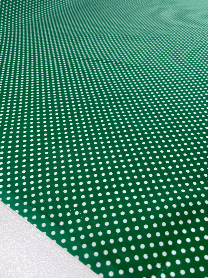 A close-up of Super Cheap Fabrics' Cotton Dots Mini in Emerald, a lightweight cotton with small white dots forming a grid, shows a perspective shift from foreground to background.