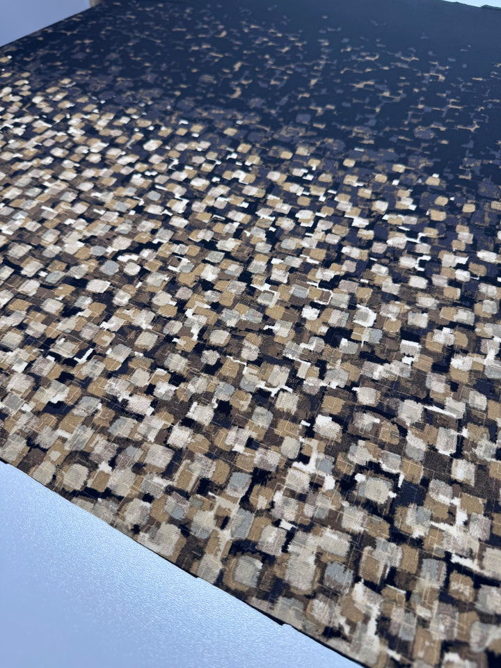 A close-up of the Designer Lycra Panel - 90cm Panel by Super Cheap Fabrics, featuring an abstract dense pattern of small squares and rectangles in brown, beige, and black on a dark background, with shapes thinning towards the top.