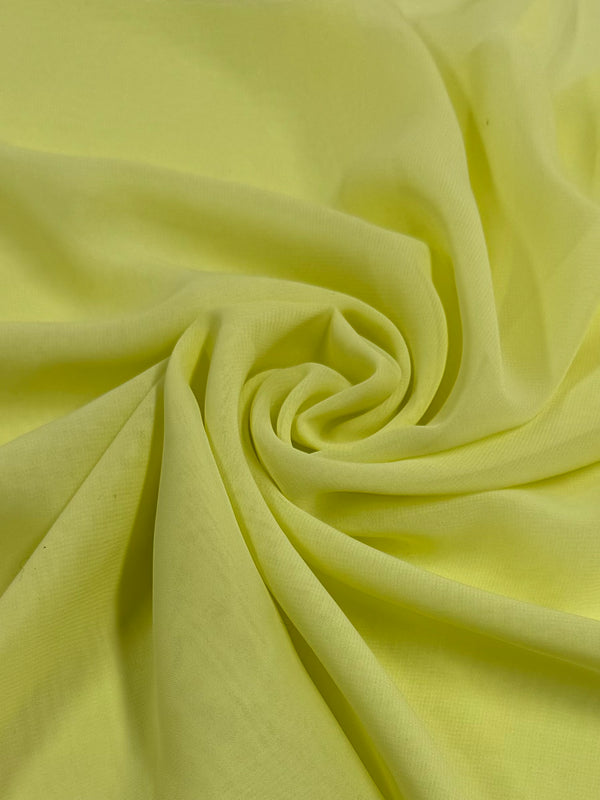 A close-up of Hi-Multi Chiffon in Elfin Yellow from Super Cheap Fabrics, measuring 150cm. The soft, sheer fabric elegantly swirls into a spiral pattern, with smooth texture and folds creating subtle shadows for depth and movement.