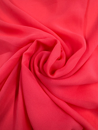 The Hi-Multi Chiffon from Super Cheap Fabrics in Calypso Coral features a bright pink sheer fabric arranged in a spiral for a textured look. Its lightweight and smooth material has subtle shading for enhanced depth, reminiscent of coral. Width: 150cm.