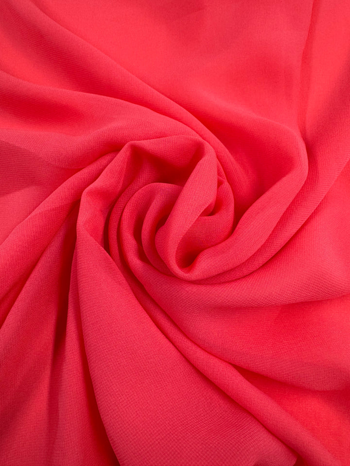 The Hi-Multi Chiffon from Super Cheap Fabrics in Calypso Coral features a bright pink sheer fabric arranged in a spiral for a textured look. Its lightweight and smooth material has subtle shading for enhanced depth, reminiscent of coral. Width: 150cm.