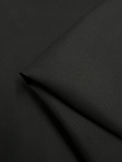 A close-up of Super Cheap Fabrics' Panama Suiting - Black (150cm), showcasing its smooth texture and clean lines.