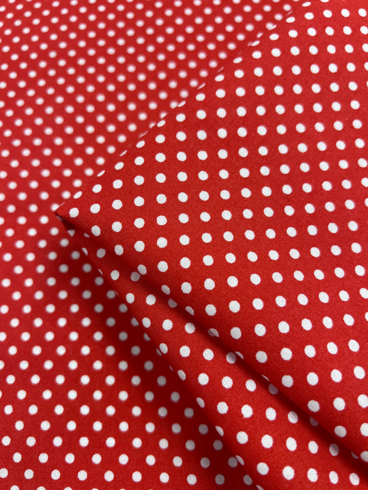 The Cotton Dots Mini - Red, by Super Cheap Fabrics, is a folded red fabric with a white polka dot pattern made from lightweight 112cm cotton.