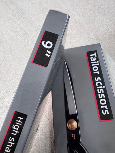 Two grey boxes on a light surface, one labeled "9'' High sha..." and the other "Tailor Scissors 9” Dressmaking Shears" by Super Cheap Fabrics, showing black shears with an ergonomic design, brass screw, and the number 9 on the blade.