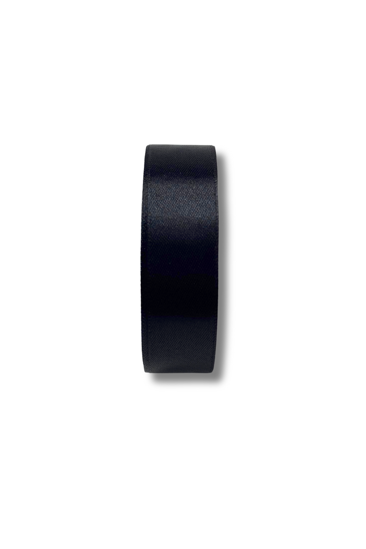 A black hockey puck is shown on a white background, viewed from the side, casting a shadow to the right, similar in shape and size to Super Cheap Fabrics' Satin Ribbon - 16 Colours - 25mm.