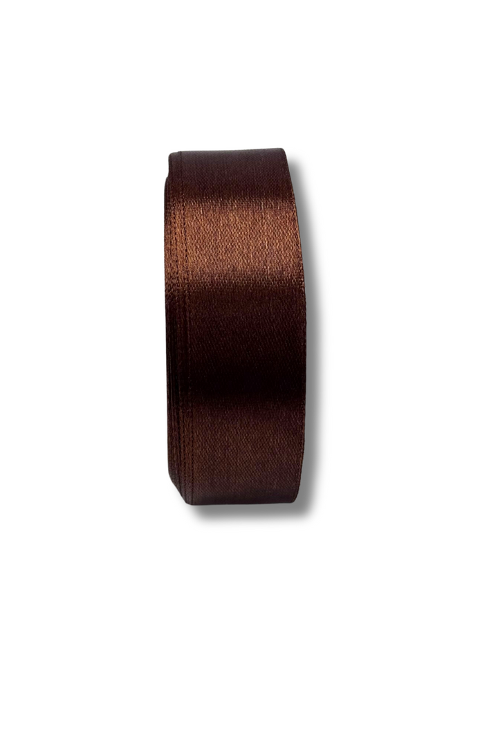 A spool of Super Cheap Fabrics’ Satin Ribbon in dark brown, 25mm wide, is neatly rolled and displayed against a white background.