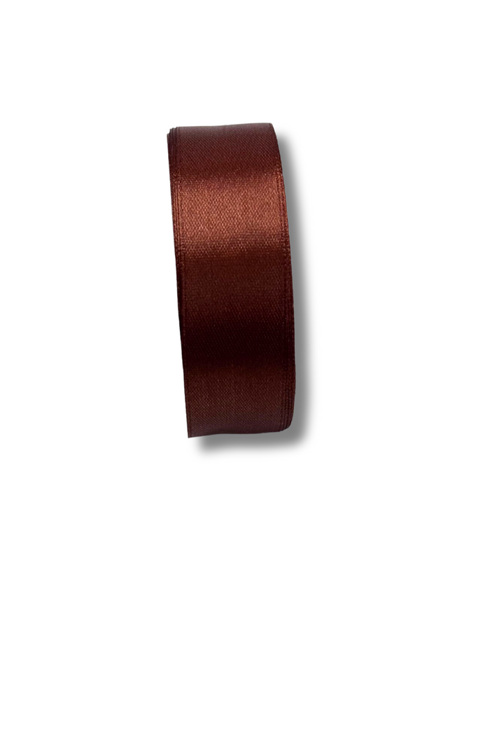 A roll of Super Cheap Fabrics Satin Ribbon - 16 Colours - 25mm stands upright on a white background, its shiny dark brown surface casting a soft shadow to the right.