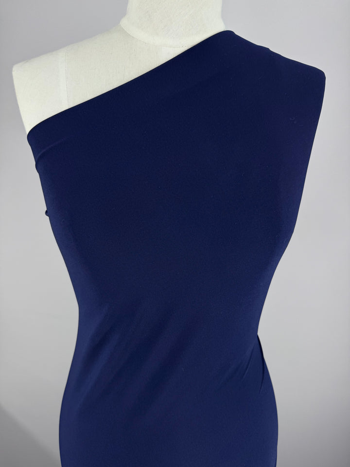 A white mannequin wears a fitted, one-shoulder dress made from Super Cheap Fabrics' ITY Knit - Navy (150cm), shown against a plain light gray background.