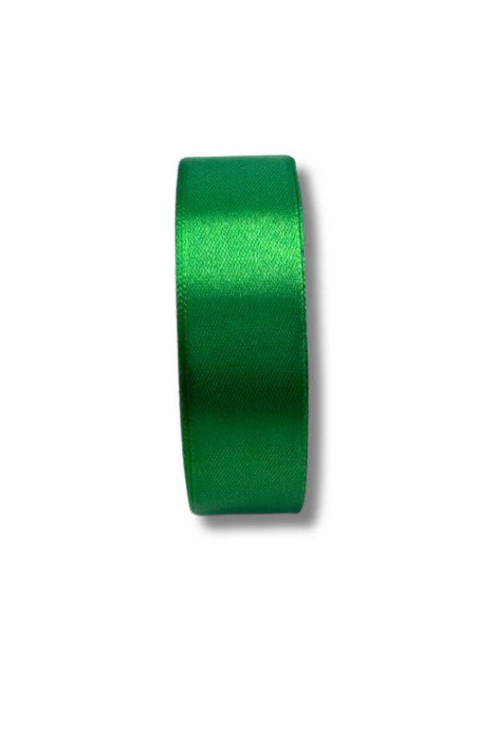 A roll of Super Cheap Fabrics Satin Ribbon (25mm, green, 16 colours) stands upright on a white background, casting a faint shadow.