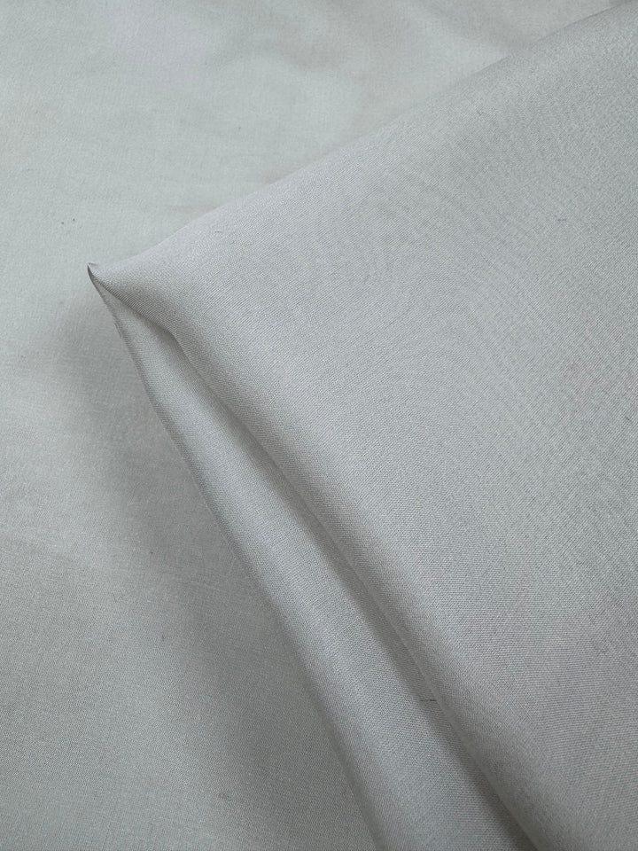 A close-up of Super Cheap Fabrics’ Pure Silk Chiffon - Oyster (140cm) shows its smooth texture and soft, light gray look—perfect as a lightweight summer fabric.