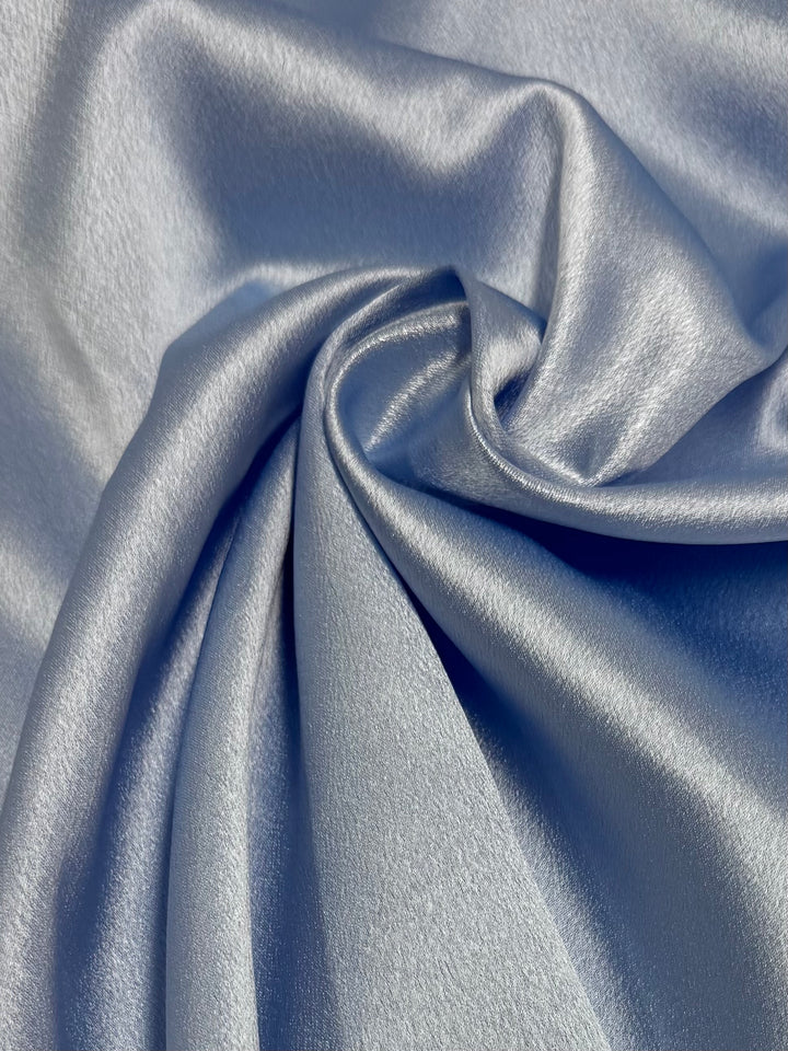 Close-up of Super Cheap Fabrics' Satin Back Crepe in Skyway (150cm), featuring smooth, shiny light blue fabric with soft folds and gentle drape—ideal for elegant fashion or eveningwear.