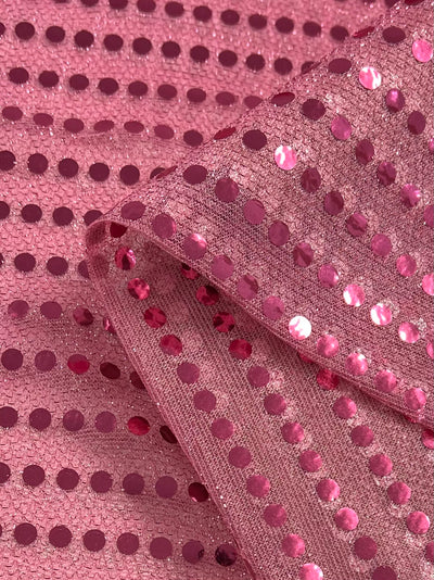 Super Cheap Fabrics' Sequin - Pink - 112cm is a mesh fabric adorned with shiny pink sequins, folded to highlight its sparkle and flexibility—ideal for standout costumes or dancewear.