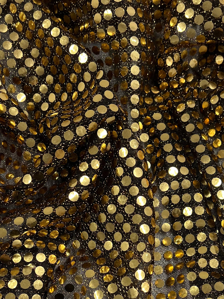 Close-up of Super Cheap Fabrics' Sequin - Black Gold - 112cm, featuring shiny gold sequins arranged in a grid on black fabric, creating a shimmering textured surface ideal for eye-catching costumes or dancewear.