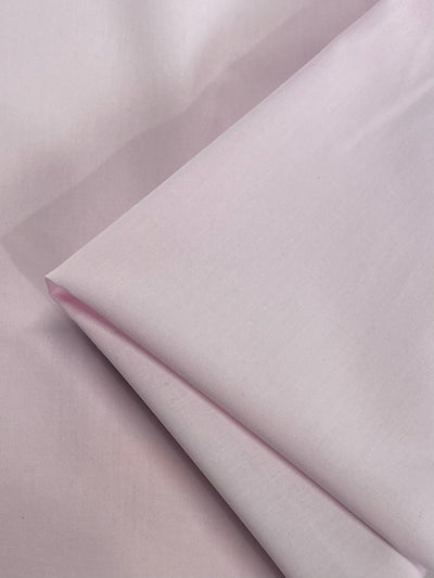 A close-up of Super Cheap Fabrics’ Plain Cotton - Pink A Boo (158cm) shows its soft, smooth texture and subtle sheen; this lightweight pink cotton is ideal for delicate designs.