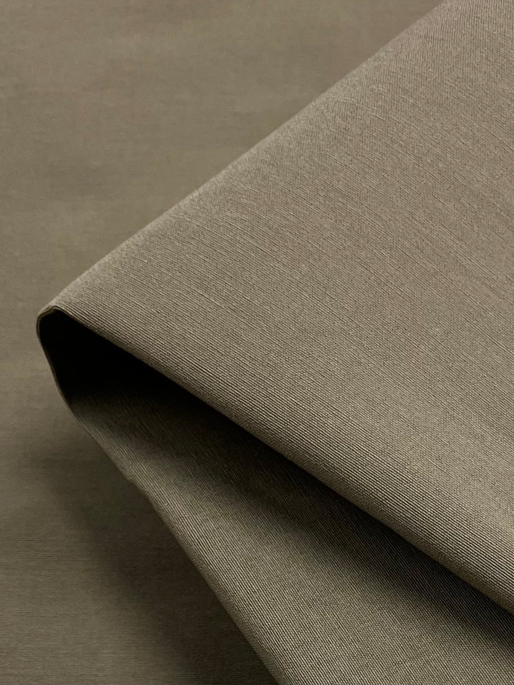 A close-up of Super Cheap Fabrics’ Stretch Bengaline - Cord - 150cm in light brown, neatly folded with a smooth, slightly textured finish, displayed on a matching fabric background.