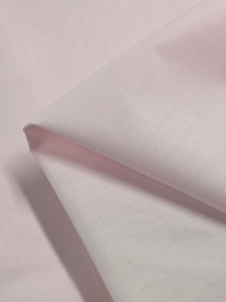 A close-up of Super Cheap Fabrics' Poplin - Baby Pink (112cm), featuring soft, smooth polyester-cotton—perfect for childrenswear and fabric projects.