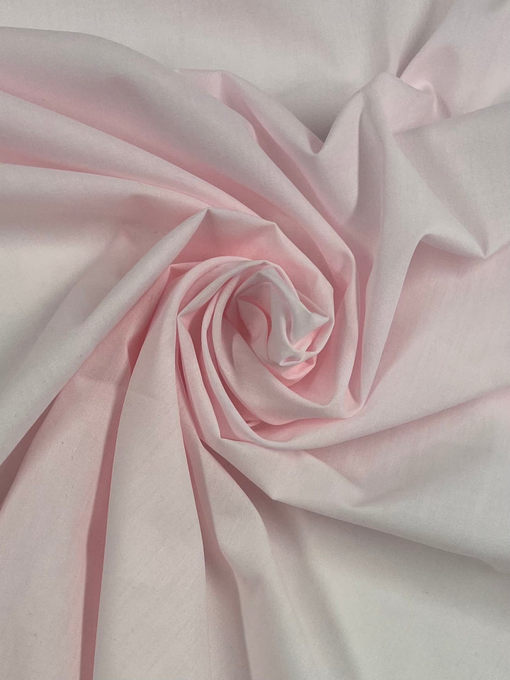 Super Cheap Fabrics’ Poplin - Baby Pink - 112cm features soft folds and smooth texture in a delicate pastel shade, ideal for childrenswear and craft projects.