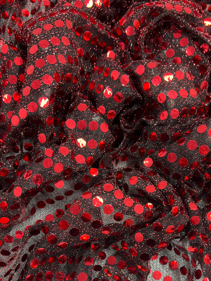 Super Cheap Fabrics' Sequin - Black & Red (112cm) features shiny red sequins on black mesh for a vibrant, textured, and slightly ruffled look—ideal for eye-catching dancewear.