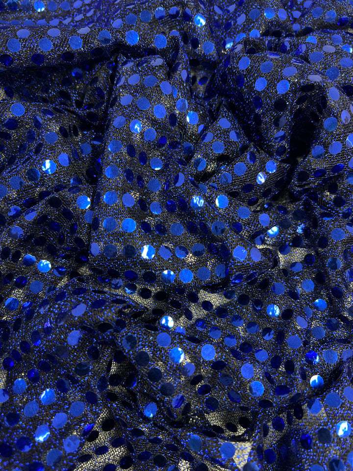 A close-up of Super Cheap Fabrics' Sequin - Sodalite Blue - 112cm shows a sparkling, textured, and reflective surface from the crumpled sequin fabric.