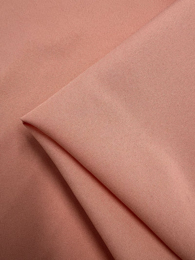 A close-up of Panama Suiting - Prairie Sunset by Super Cheap Fabrics, a 150cm wide, medium weight polyester fabric in light pink with a smooth, subtly textured surface and fine diagonal lines.