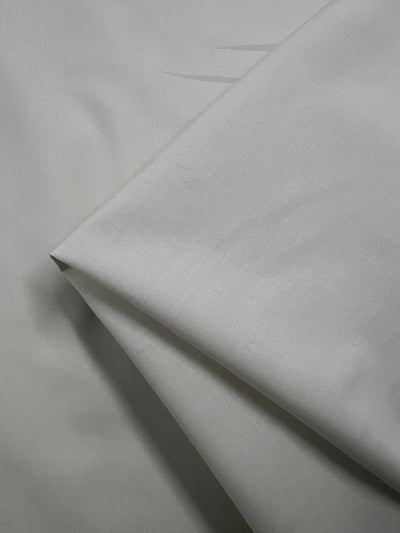 A close-up of several layers of Plain Cotton - Birch - 150cm from Super Cheap Fabrics, showing its smooth, slightly textured look. This lightweight fabric is made from 100% cotton and measures 150cm wide.