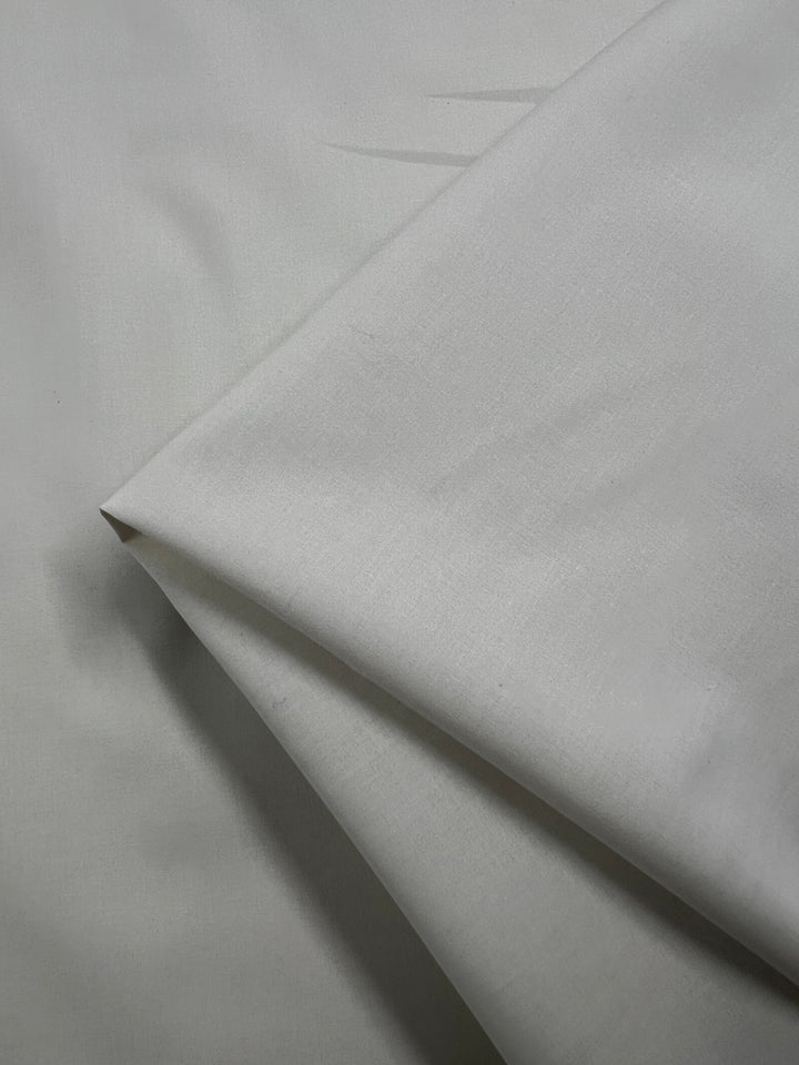 A close-up of several layers of Plain Cotton - Birch - 150cm from Super Cheap Fabrics, showing its smooth, slightly textured look. This lightweight fabric is made from 100% cotton and measures 150cm wide.