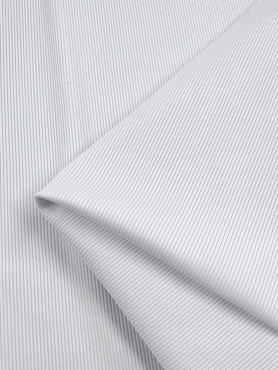 A close-up of Super Cheap Fabrics’ Rib Knit 1x1 - White - 124cm shows neatly folded medium-weight fabric with fine vertical blue pinstripes on a white background, creating a clean, orderly appearance.