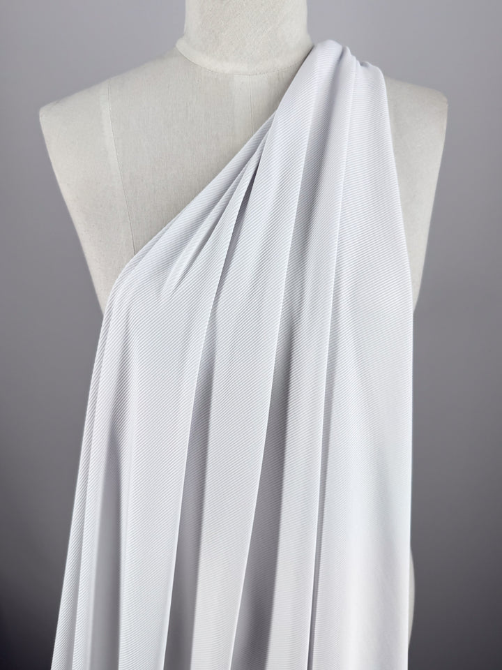 A white mannequin features Super Cheap Fabrics' Rib Knit 1x1 in an elegant toga-like style over one shoulder, with the stretch fabric's texture adding depth against a neutral gray background to enhance its classic appeal.