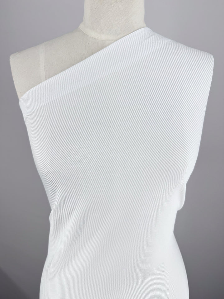 A mannequin displays a white, one-shoulder dress made from Super Cheap Fabrics' Rib Knit 1x1 (124cm) against a gray background. The minimalist design and subtly textured medium-weight rib knit enhance the single-shoulder style.
