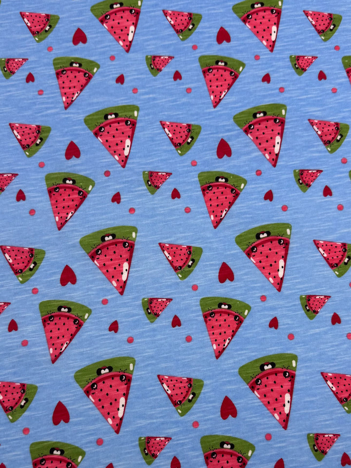 The "Printed Jersey - Sandia - 145cm" by Super Cheap Fabrics is a medium weight fabric with cartoon watermelon slices featuring happy faces, a green rind, red flesh, black seeds, and small red hearts on a light blue background, creating a playful and cheerful multi-colour design.