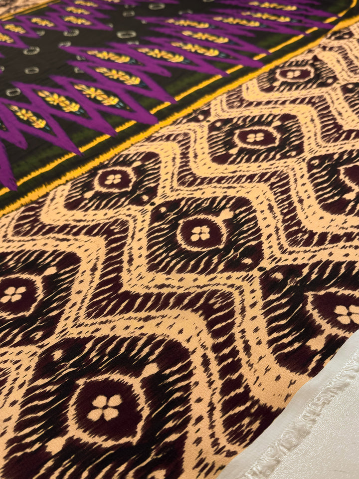 Close-up of Super Cheap Fabrics’ Printed Viscose - Regal Ikat (145cm), showcasing diamond and floral motifs in brown and cream with black, yellow, and purple geometric designs—perfect for unique designer projects.
