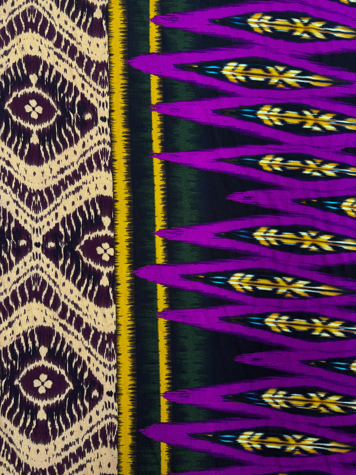 Super Cheap Fabrics’ Printed Viscose - Regal Ikat (145cm) features two striking patterns: cream and dark purple diamonds on one side, and bold purple, yellow, green, and black geometric jagged lines on the other.