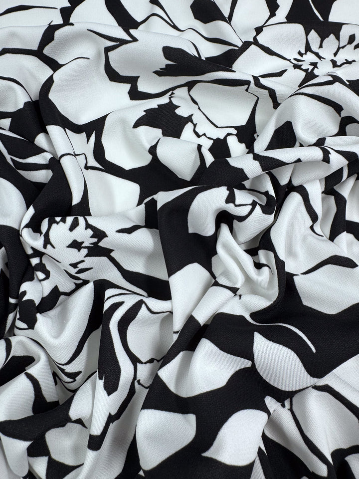 The Printed Jersey - Shadow Garden by Super Cheap Fabrics is a black and white mid-weight fabric with an abstract floral pattern. Its crumpled polyester surface creates dynamic shapes and shadows, ideal for clothing material. Width: 150cm.