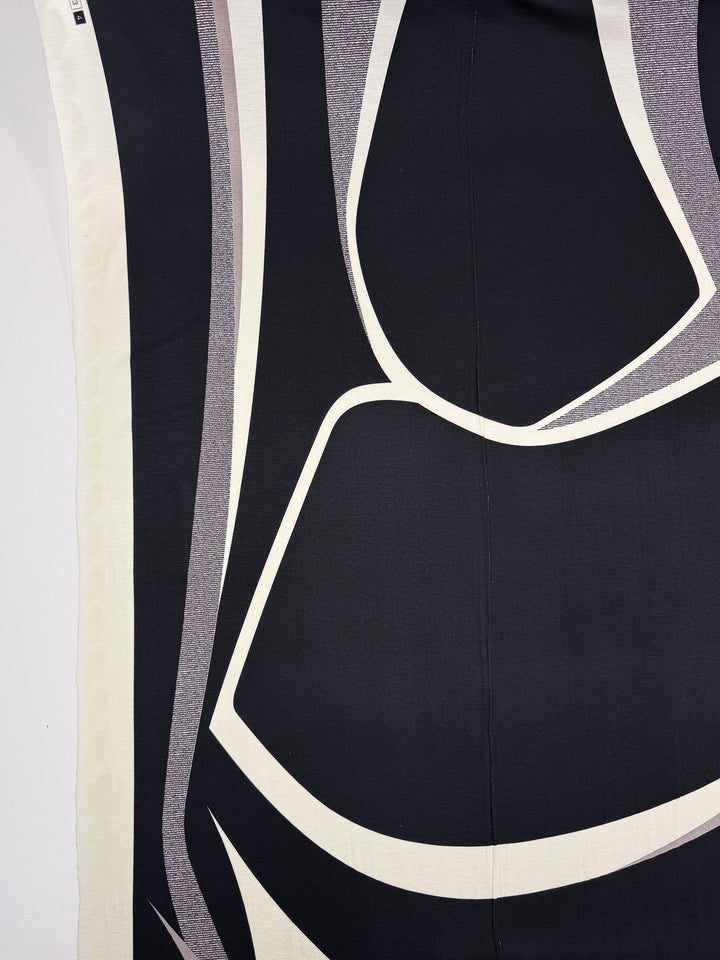A close-up of Super Cheap Fabrics’ Viscose Knit - Curve (145cm), showing stretch fabric with an abstract black, white, and gray geometric pattern of curved lines and bold shapes.