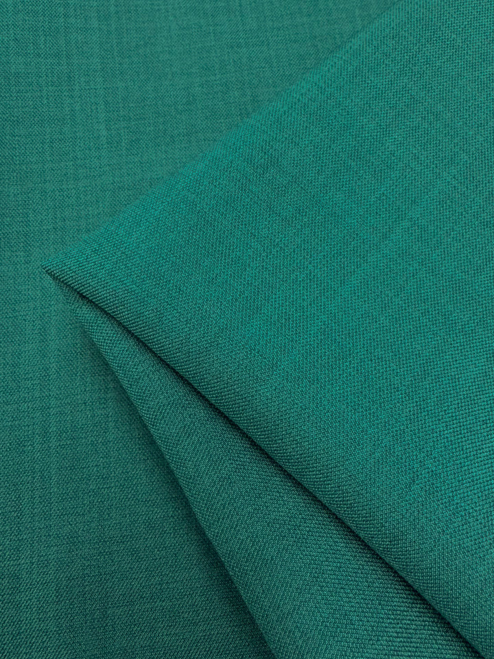 Folded Twill Suiting - Ivy (150cm) by Super Cheap Fabrics in teal-green with a subtle diagonal weave, layered on matching fabric to showcase its versatile style.