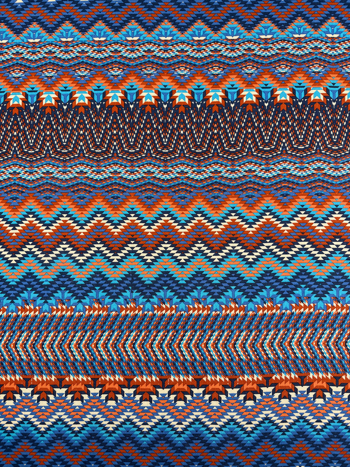 The Super Cheap Fabrics Printed Viscose - Zulu - 150cm features a vibrant, geometric zigzag pattern in blue, orange, red, and white, evoking traditional woven textiles with its symmetrical and sharp design.