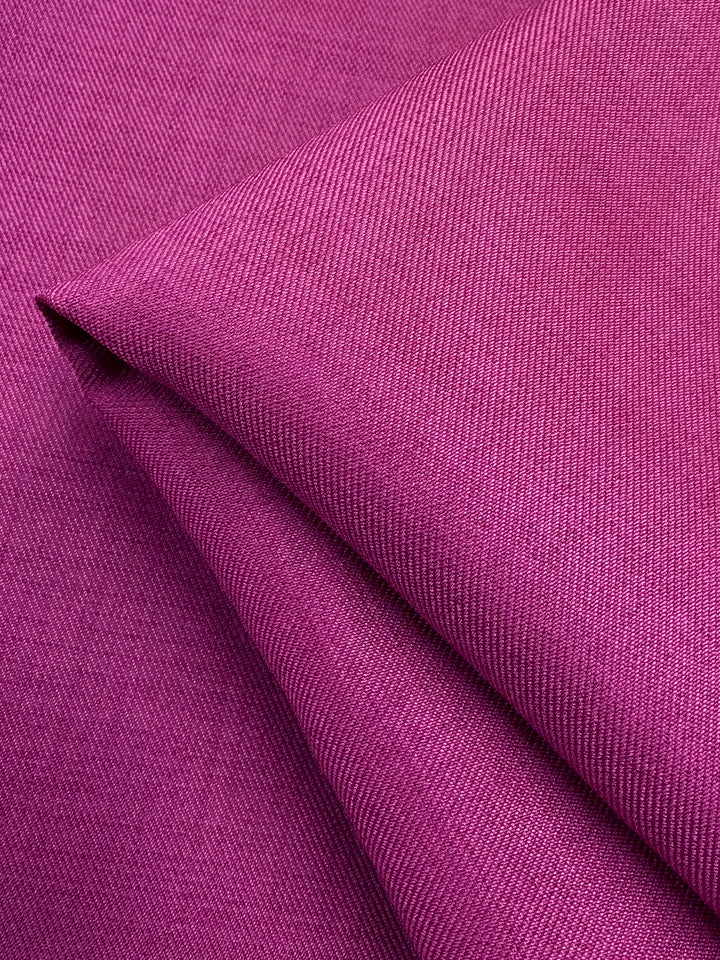 A close-up of Twill Suiting - Fuchsia Rose by Super Cheap Fabrics shows its folded, textured surface with visible diagonal lines and a smooth, slightly shiny finish; fabric width is 150cm.