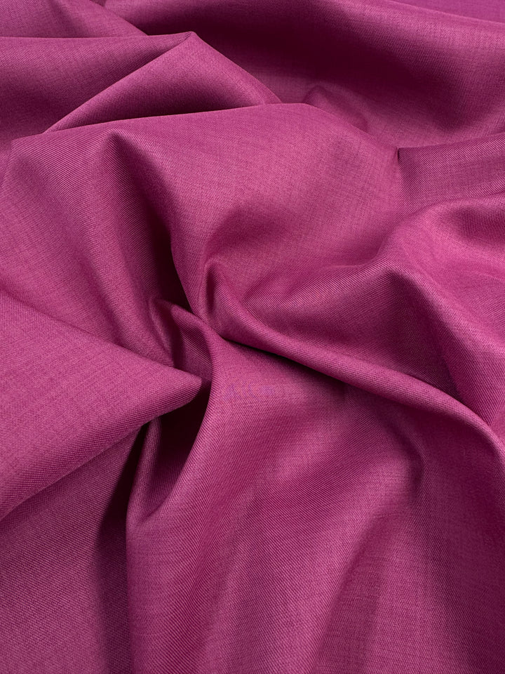 A close-up of Super Cheap Fabrics' Twill Suiting in Fuchsia Rose (150cm), showing its soft folds, subtle texture, gentle diagonal weave, and natural creases in polyester.