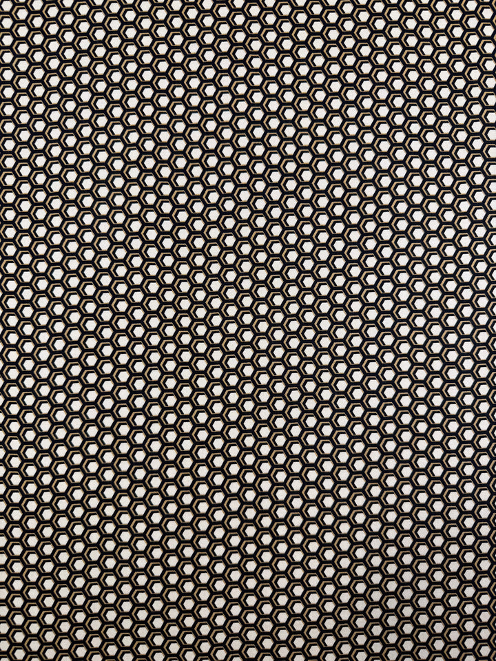 A close-up of Super Cheap Fabrics' Printed Viscose - Hive - 145cm shows its black circular mesh pattern, reminiscent of Italian textiles. The illuminated background highlights the geometric grid and fine detail of this unique fabric.