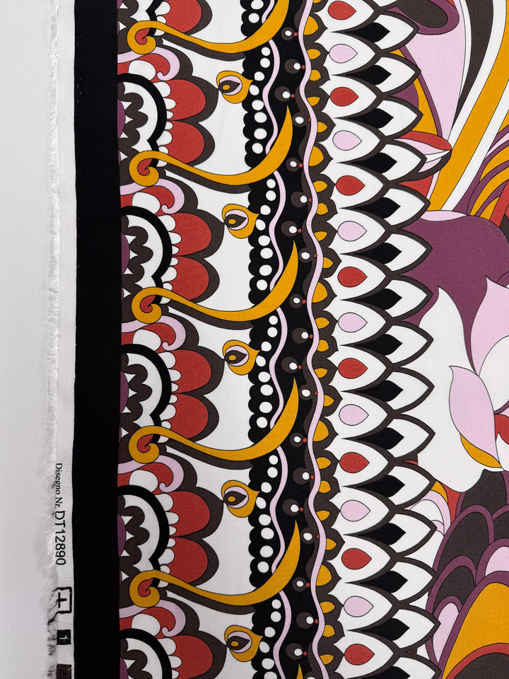 A close-up of Super Cheap Fabrics’ Printed Viscose - Fantasia (145cm) shows lightweight fabric with bold red, yellow, black, and white scalloped and geometric patterns plus floral motifs. The edge and printed product number appear on the left.
