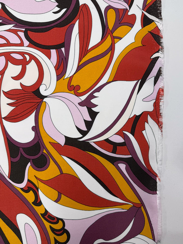 The Printed Viscose - Fantasia from Super Cheap Fabrics features a lightweight, retro-inspired abstract pattern with swirling red, orange, purple, black, and white shapes. Fabric width is 145cm and the right side has a visible edge.